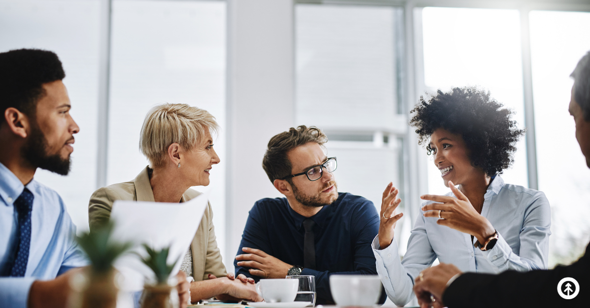 A group of people sitting around a conference table listening intently to one person speaking. 