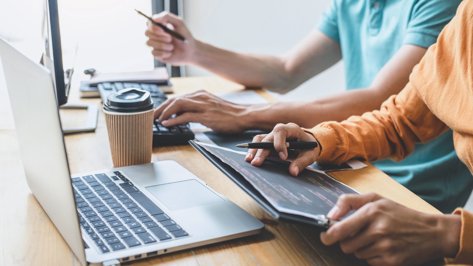 Two people working together side-by-side to analyze data on laptop computers.