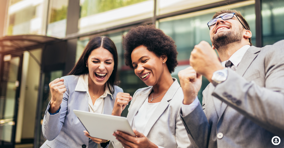 Three business people celebrating good news that's just been communicated through a mobile device.