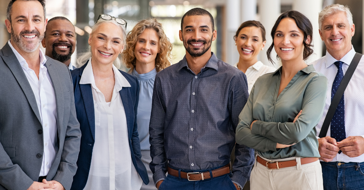 A group of professionals smiling and standing together smiling straight at the camera. 