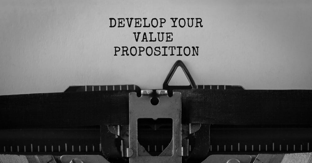 “Develop Your Value Proposition” typed on a piece of paper with an old typewriter in the forefront. 