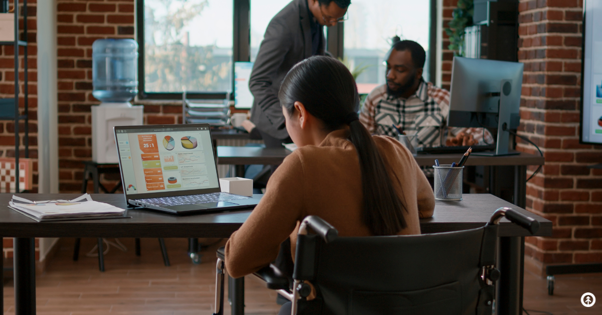 A person reading data on a laptop computer in an office setting. 