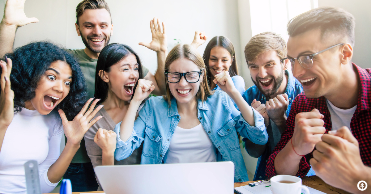 An excited group of people looking at great news on a laptop screen.