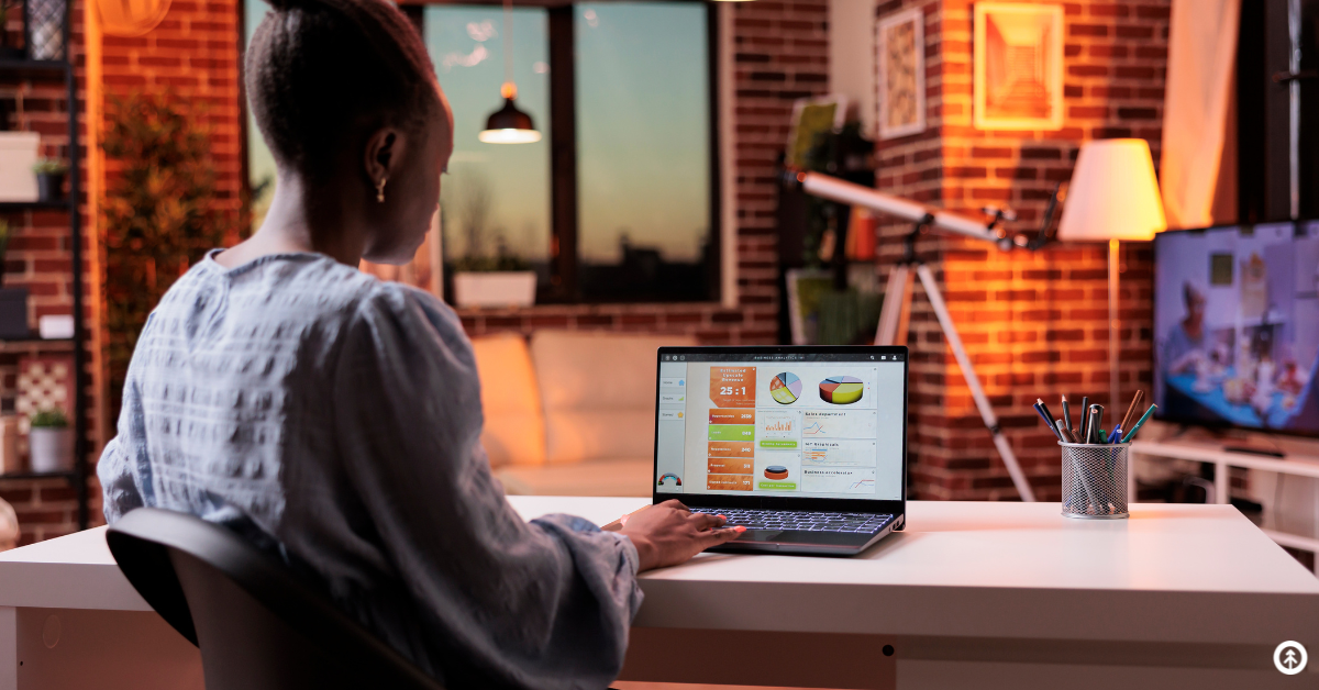 A person sitting in an office reading data points from a laptop screen. 