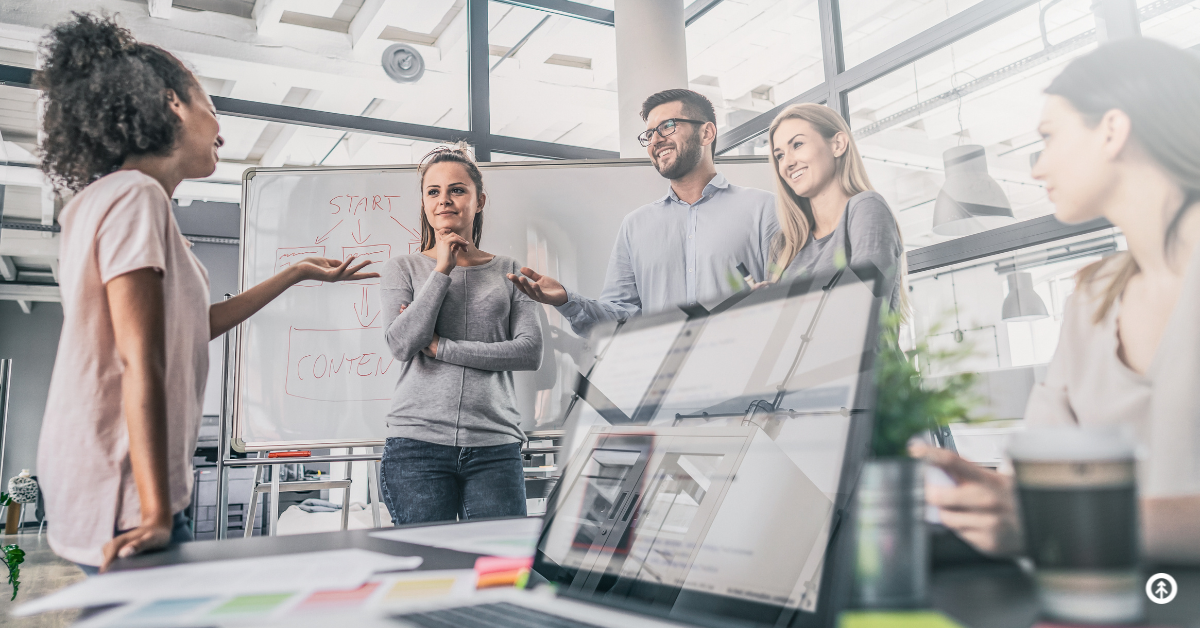 A marketing professional talking to a small team in a modern workspace.