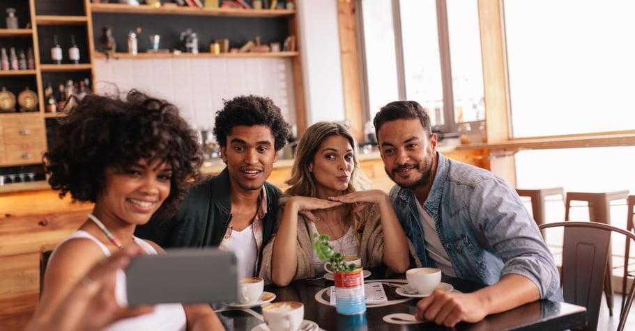 A group of friends taking a selfie in a coffee shop for social media