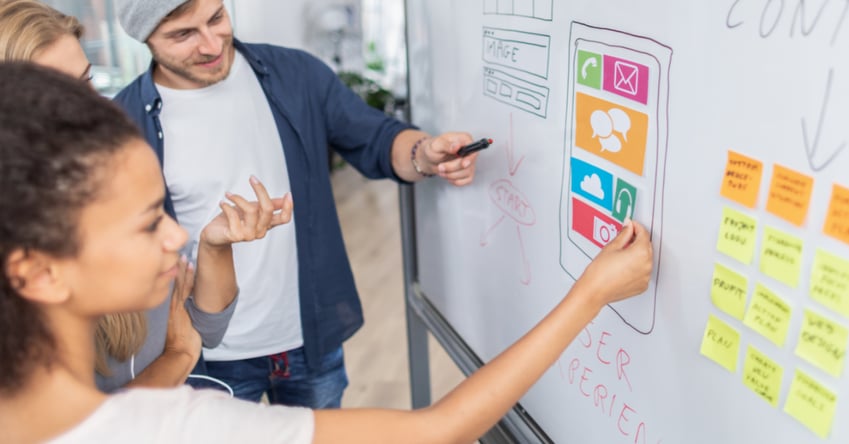 A team designing a website UX on a whiteboard