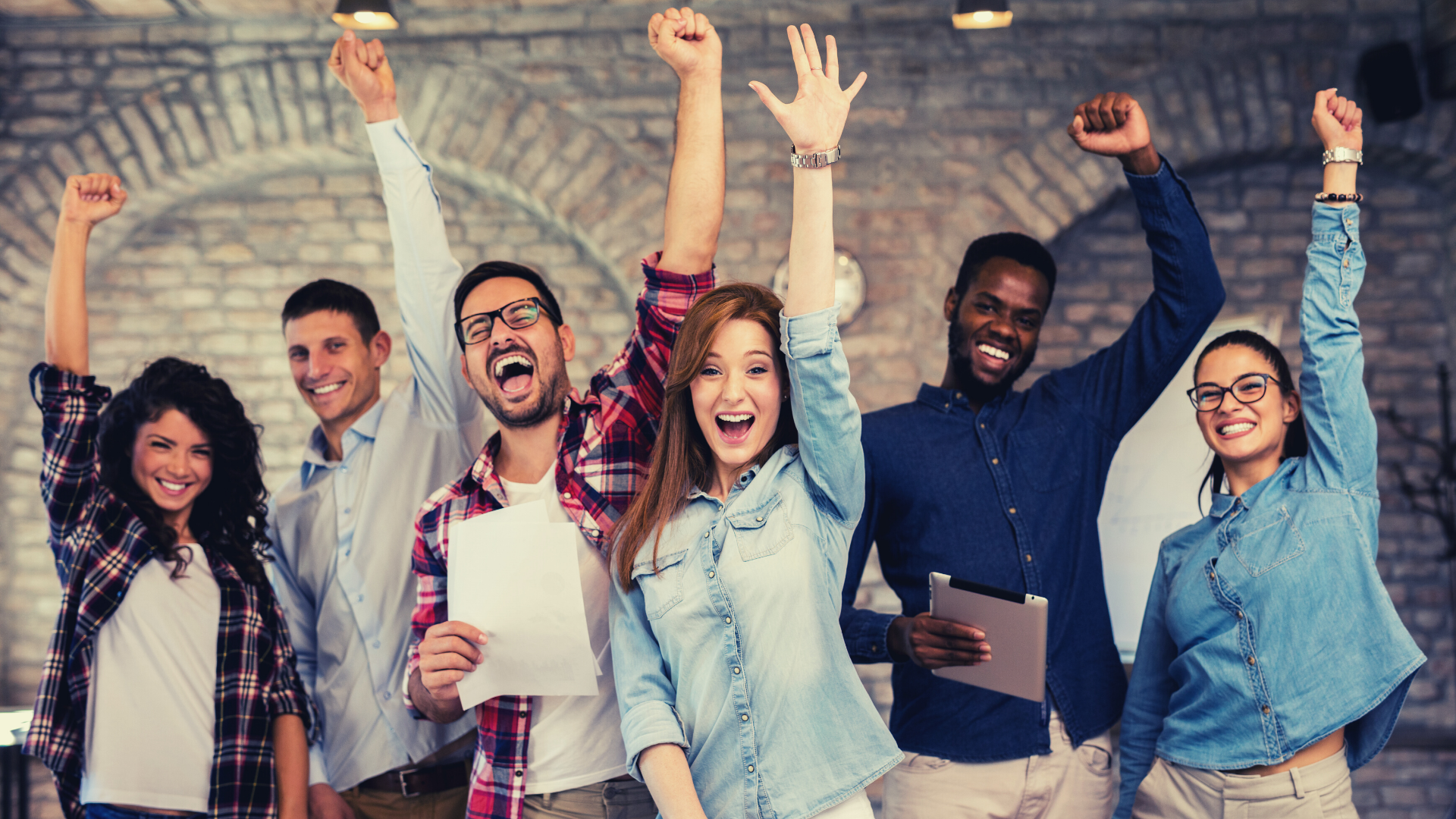 A team of co-workers celebrates a big win in a casual office setting. 