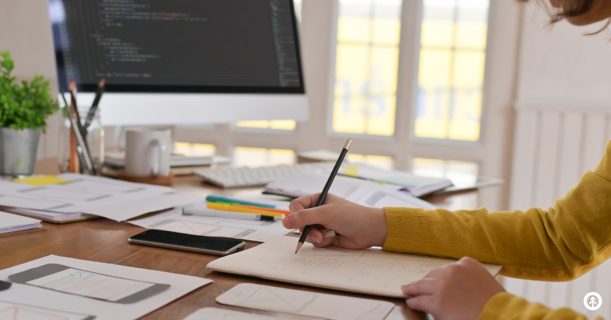 A website designer sketching ideas for a site on paper with a pencil.