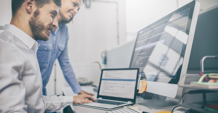 Two team members developing a website on a laptop and desktop computer