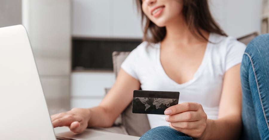 A woman using a credit card to shop online at home