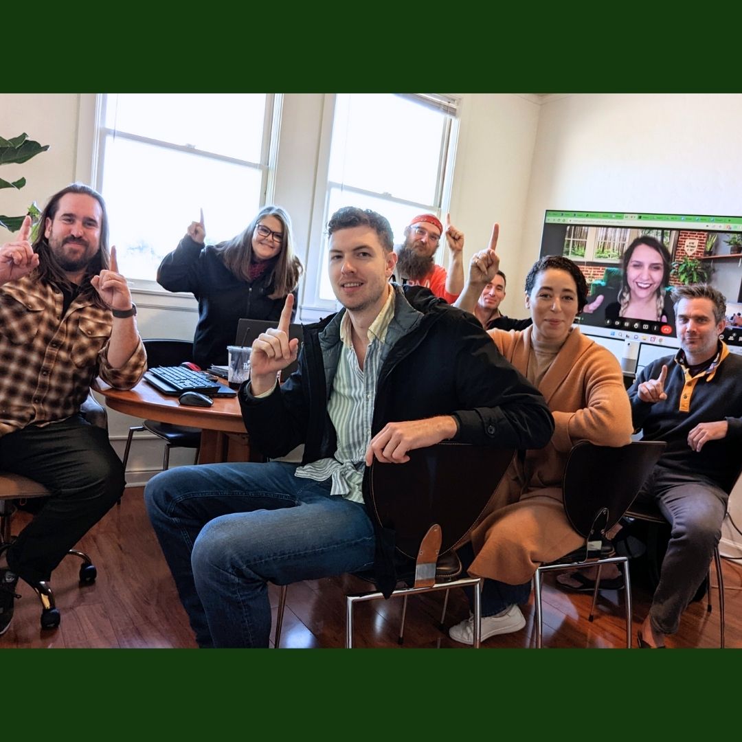 Eight Growth team members around a conference table holding up their index fingers to show that our team is number one. 
